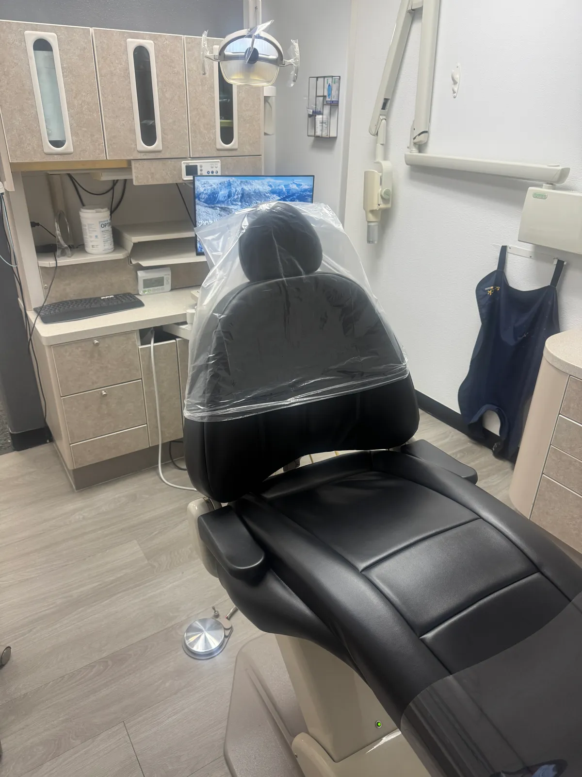 Treatment room at Navarro Dentistry with a black dental chair, overhead light, and monitor